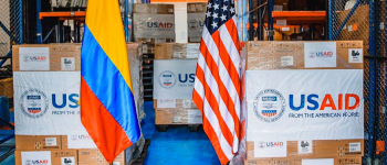 Imagen de las cajas con la donación de USAID acompañadas de las banderas de Colombia y de Estados Unidos