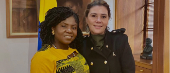 La directora Eleonora Betancur González a la derecha, a la izquierda la vicepresidenta Francia Marques, detrás de ellas la bandera de Colombia
