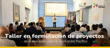 Personas reunidas en un auditorio en donde hay una persona exponiendo en la tarima sobre taller en formulación de proyectos de cooperación para Alianza del Pacífico. 